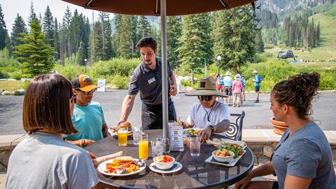 A group of friends get food delivered to table at Honeycomb Grill at Solitude Mountain Resort. 