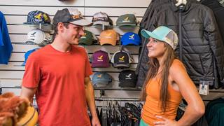 A couple checks out logo baseball caps in Canyon Fever retail store at Solitude Mountain Resort